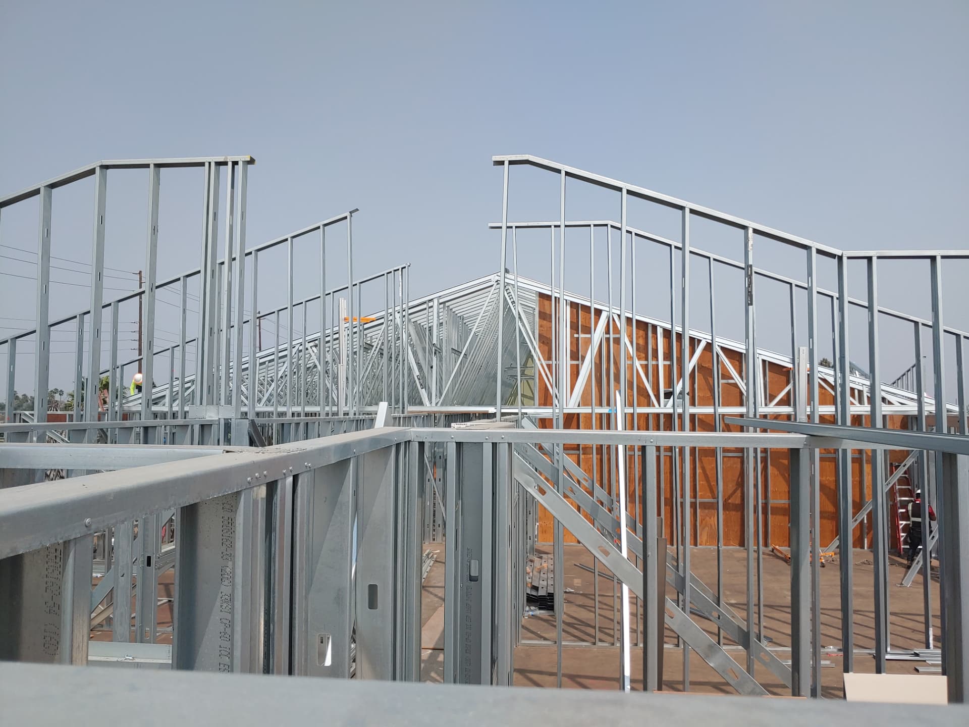 Residential cold-formed steel roof and truss framing integrated with wall framing on a custom home under construction.