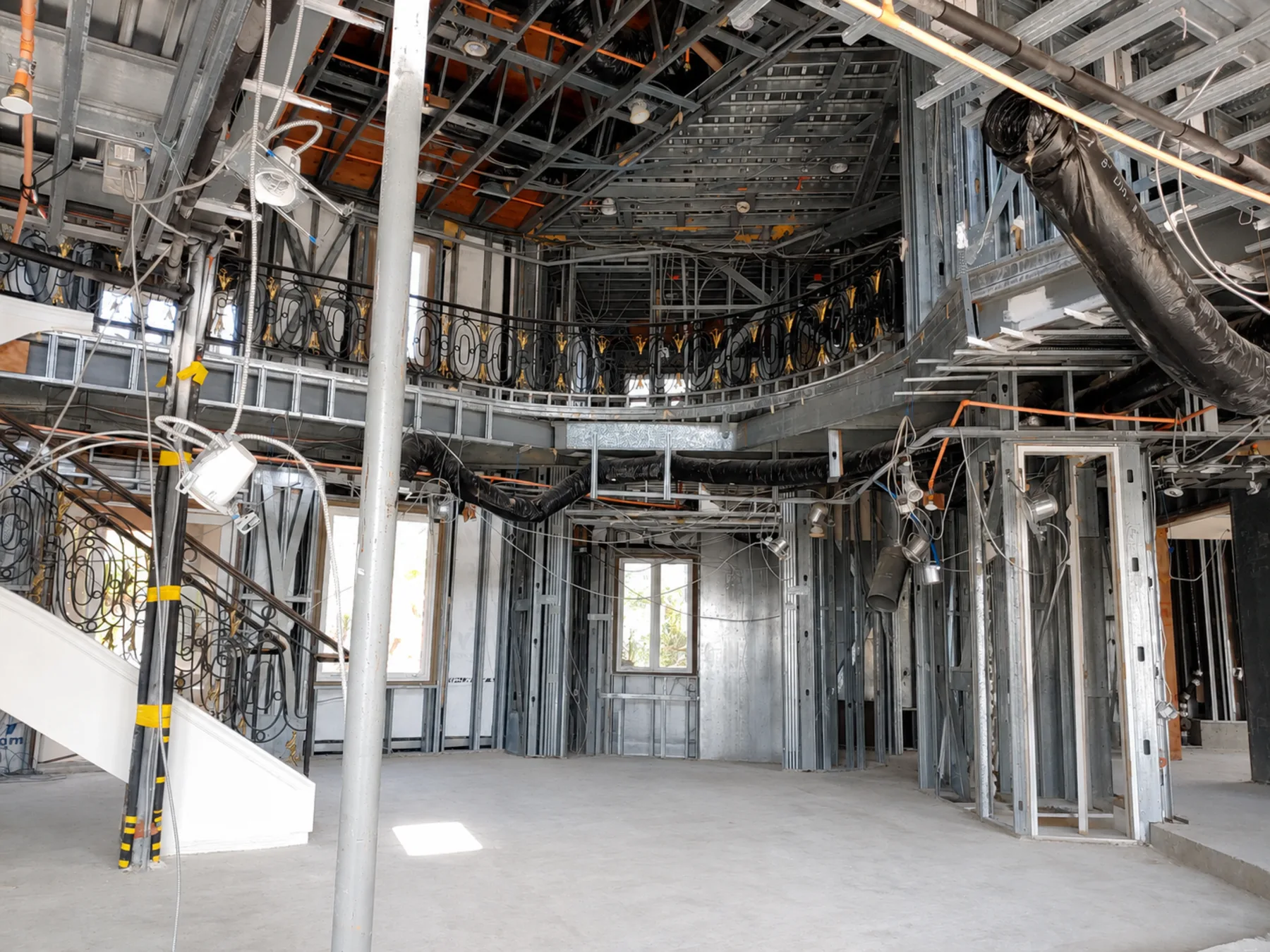 Two-story residential great room framed in cold-formed steel with steel wall studs, ceiling framing and a curved balcony structure