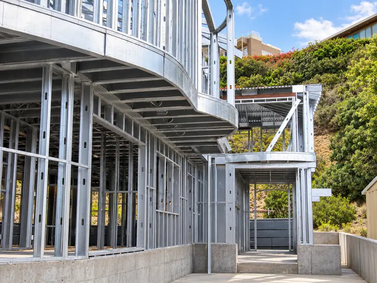 Exterior cold-formed steel framing with custom curved residential geometry.