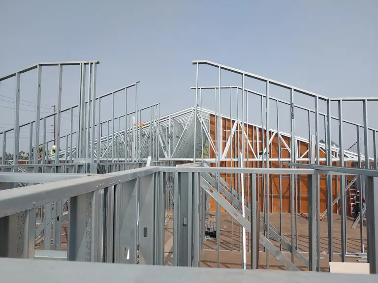 Residential cold-formed steel roof and truss framing integrated with wall framing on a custom home under construction.